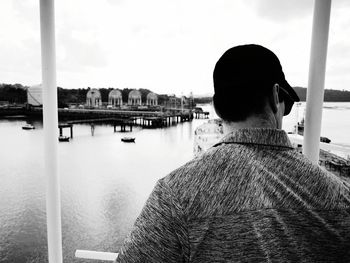 Rear view of man looking at river against sky