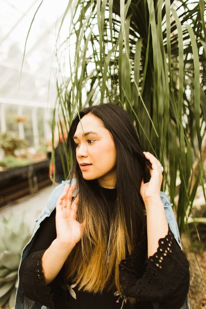 PORTRAIT OF YOUNG WOMAN SITTING IN PARK