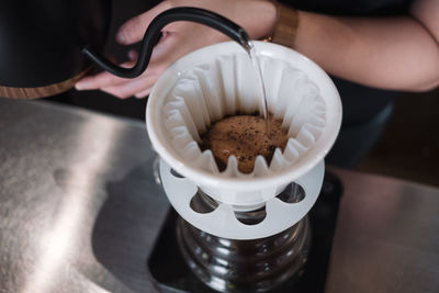 High angle view of hand holding coffee cup on table