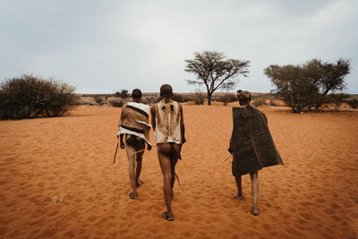 Rear view of people walking on sand