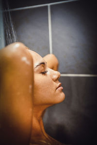 Close-up of woman taking shower in bathroom