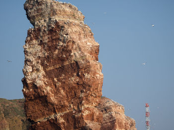 Low angle view of rock formation against clear blue sky