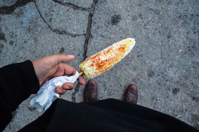 Low section of person holding corn on street