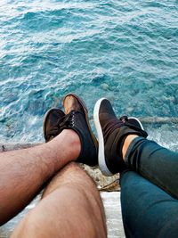 Low section of men sitting by sea