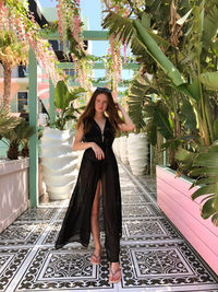 Portrait of teenage girl standing on footpath against plants