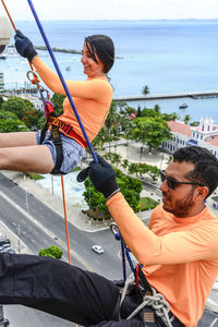 A man and a woman, rappellists, going down the elevator. very tall monument. salvador bahia brazil.