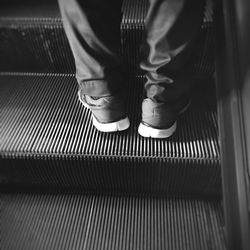 Low section of man standing on escalator