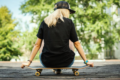 Rear view of woman sitting on skateboard