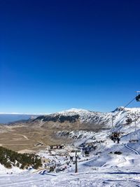 Snow covered landscape against clear blue sky
