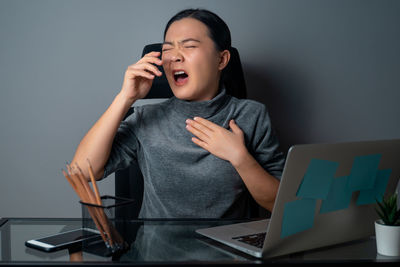Mid adult man using mobile phone while sitting on table