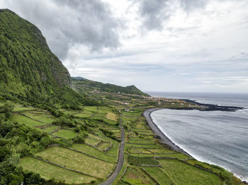 Scenic view of landscape by sea against sky