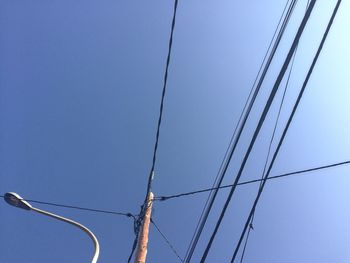 Low angle view of electricity pylon against blue sky