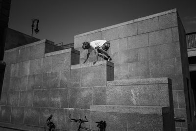 A man in shorts climbs over a wall