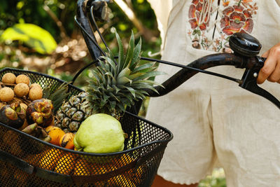 Midsection of woman picking vegetables in bicycle