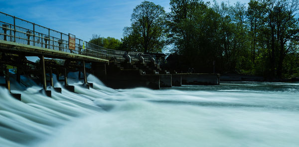 Water flowing on dam against sky