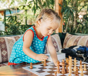 Cute girl playing chess at backyard