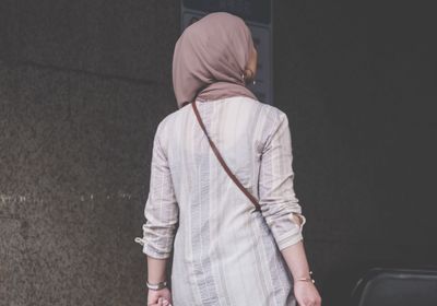 Rear view of woman wearing hijab while standing against wall