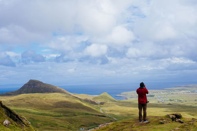 Rear view of woman standing on mountain against cloudy sky