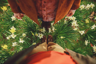 Low section of man and woman standing on field by flowers