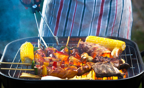 Midsection of man preparing food on barbecue grill