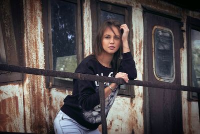 Portrait of young woman standing outside abandoned house