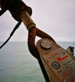 Close-up of padlocks on rusty metal against sky