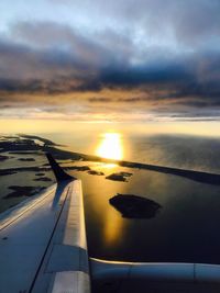 Airplane flying over clouds during sunset
