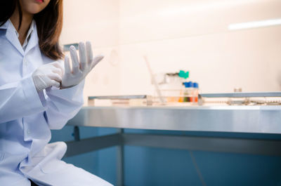 Midsection of woman sitting by table in laboratory
