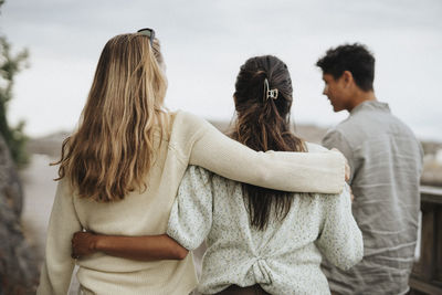 Rear view of female friends walking with arms around