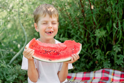 Boy holding watermelon while standing outdoors