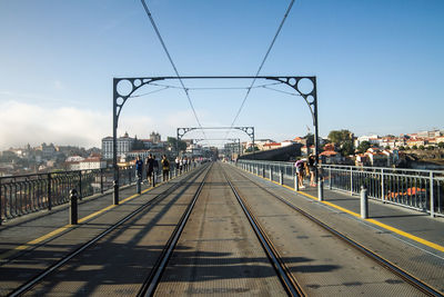 Group of people on railroad tracks in city against sky