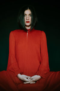 Portrait of young woman against black background