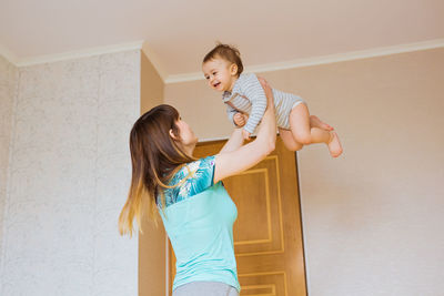 Mother and daughter standing against wall