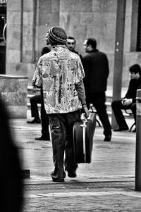 Rear view of men walking on street in city