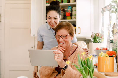 Portrait of happy young woman using smart phone at home