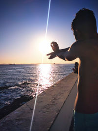 Woman on beach against sky during sunset