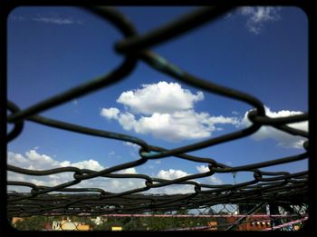 Low angle view of chainlink fence against blue sky