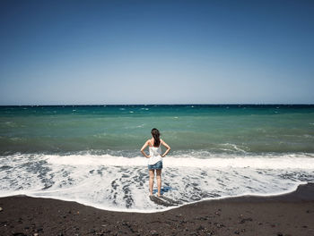 Woman dressed from behind while observing the immensity of the sea.