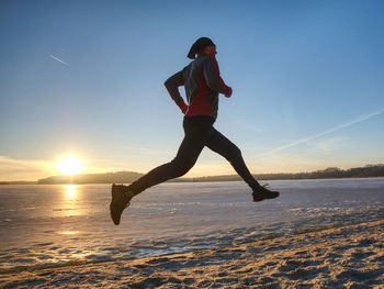 Couple runners running in winter nature. frozen river beach run. copy space.