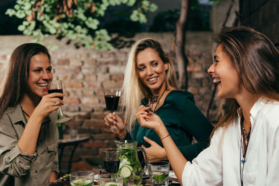 Smiling young woman drinking glass outdoors