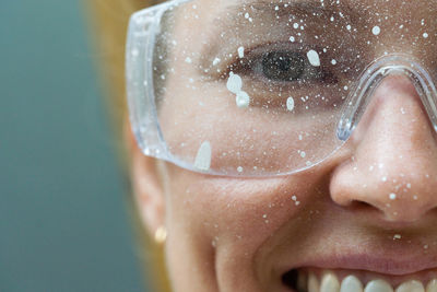 Close up of a smiling woman face wearing protective glasses covered in paint