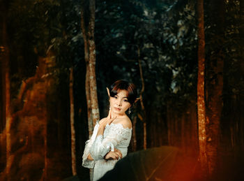 Woman standing by tree trunk in forest