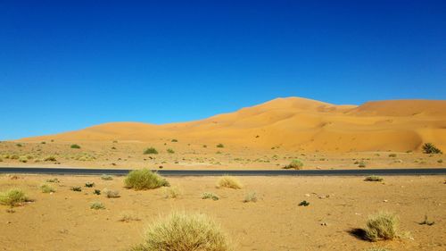 Scenic view of desert against clear blue sky