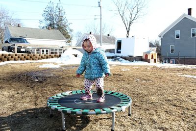 Full length of girl standing on trampoline in snow against sky