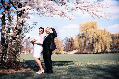 Full length of friends standing on cherry tree