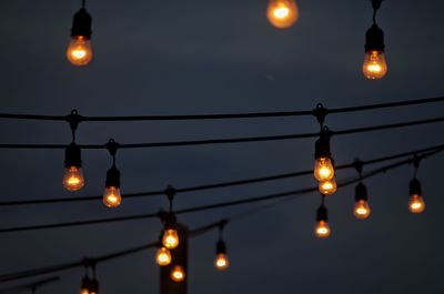 Low angle view of illuminated lamps against sky at night