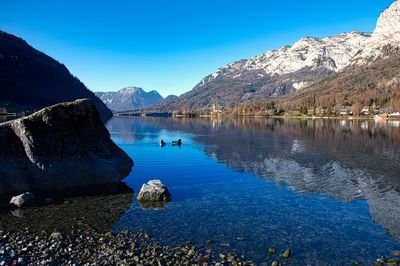 Scenic view of lake and mountains against clear blue sky