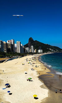 Scenic view of beach and buildings against clear blue sky