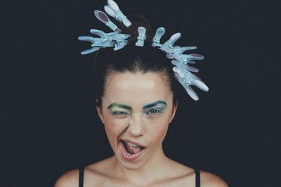 Close-up portrait of woman making face against black background