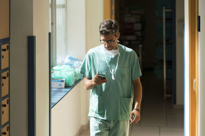 Serious surgeon using smartphone